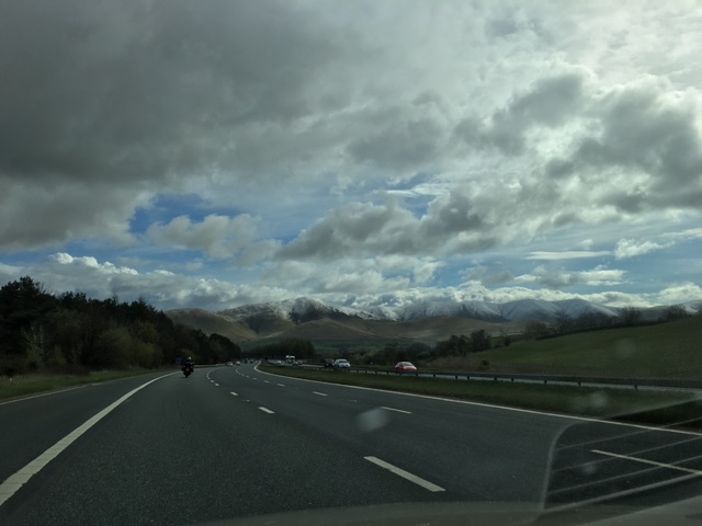 Three lane motorway with snowy mountain range in the distance